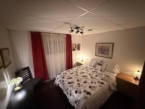 Une chambre d’hôtel avec un lit, des lampes de chevet, une table avec une lampe, une chaise et une fenêtre avec des rideaux.