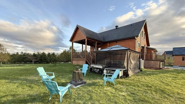 Une cabane en bois dotée d’un porche couvert, d’un barbecue et de mobilier d’extérieur.