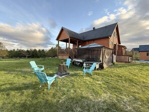 Une cabane en bois dotée d’un porche couvert, d’un barbecue et de mobilier d’extérieur.