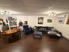 Een woonkamer met een eettafel, banken en een boekenkast.