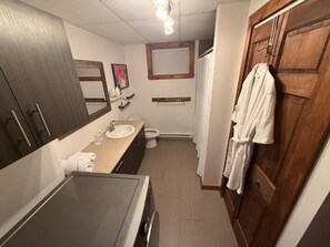 Une salle de bain équipée d’un lavabo, d’un miroir, d’un porte-serviettes et d’une porte en bois.