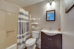 Een badkamer met een douche, toilet en een wastafel met spiegel.