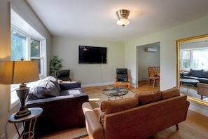 A living room with a sofa, a coffee table, a TV mounted on the wall, and a ceiling fan.