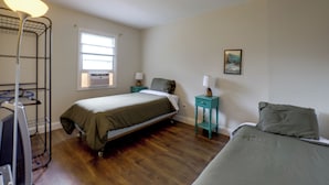 Een slaapkamer met een bed, bureau, stoel, lamp en raam.