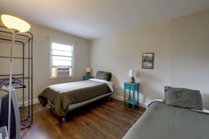 Een slaapkamer met een bed, bureau, stoel, lamp en raam.