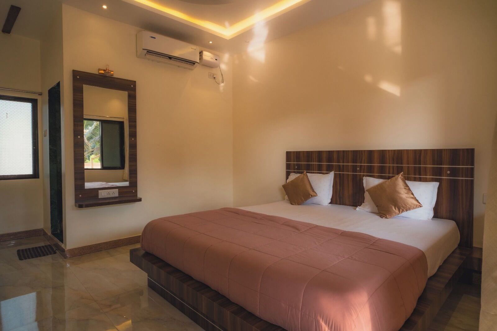 Une chambre d’hôtel avec un grand lit, un climatiseur fixé au mur, un miroir et une fenêtre.