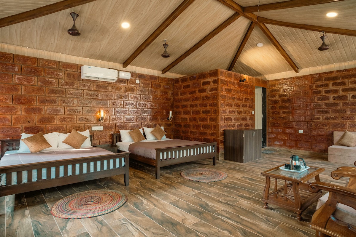 A rustic room with two wooden beds, a brick wall, and a ceiling with wooden beams.