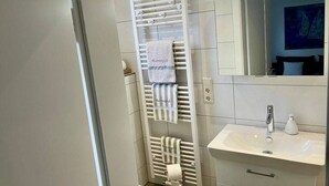 Ein Badezimmer mit weißem Handtuchhalter, einem Waschbecken und einem Spiegel.