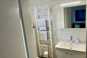 Un baño con toallero blanco, lavamanos y espejo.