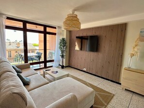A modern living room with a sofa, coffee table, and a TV mounted on a wooden panel wall. - Ocean view • Beach 90 m away • Serves 6 • Air Conditioning • Parking (Saint-Mandrier-sur-Mer)