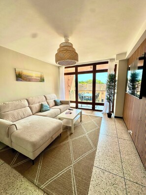 A modern living room with a sofa, coffee table, and a large window offering a view of the outdoors. - Ocean view • Beach 90 m away • Serves 6 • Air Conditioning • Parking (Saint-Mandrier-sur-Mer)