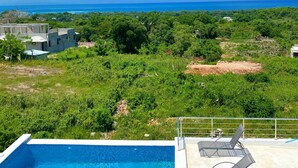 A swimming pool with lounge chairs, a view of the ocean, and a building under construction. - Villa with pool near Laguna Gri-Grí and beaches (Río San Juan)