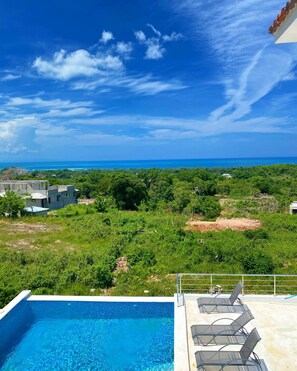A swimming pool with lounge chairs, a view of the ocean, and a building under construction. - Villa with pool near Laguna Gri-Grí and beaches (Río San Juan)