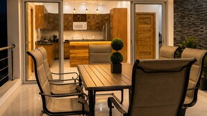 A modern kitchen with a dining area, featuring a wooden table and chairs, a ceiling fan, and a view into the adjacent living space. - Villa with pool near Laguna Gri-Grí and beaches (Río San Juan)