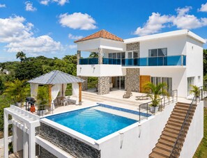 A modern two-story house with a swimming pool, outdoor seating, and a staircase leading to the upper level. - Villa with pool near Laguna Gri-Grí and beaches (Río San Juan)