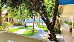 A hotel corridor with a pathway lined by trees and a building with a tiled roof.