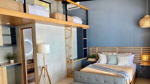 A modern bedroom with a loft bed, bedside table, lamp, and a small plant.