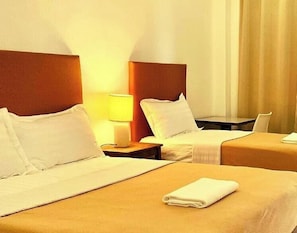 A hotel room with two beds, a nightstand with a lamp, and a view of the outside. - Marzon Beach Resort (Boracay Island)