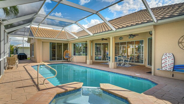 Une piscine extérieure couverte, dotée d’un patio, d’un ventilateur de plafond et décorée avec une planche de surf.
