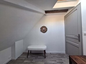 A small, enclosed room with a white bench, a wooden door, and a wall-mounted decorative item. - Garden house with stunning mountain views near the lake – Aux Rousses, Réallon (Réallon)