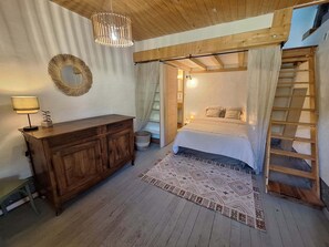 Una camera da letto con un letto di legno, un comodino, una lampada, uno specchio e una scala.