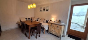 A dining area with a wooden table, chairs, a sofa, and a cabinet. - Garden house with stunning mountain views near the lake – Aux Rousses, Réallon (Réallon)