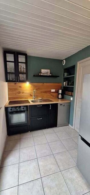 A compact kitchen with a wooden countertop, a sink, a dishwasher, and a stove. - Garden house with stunning mountain views near the lake – Aux Rousses, Réallon (Réallon)