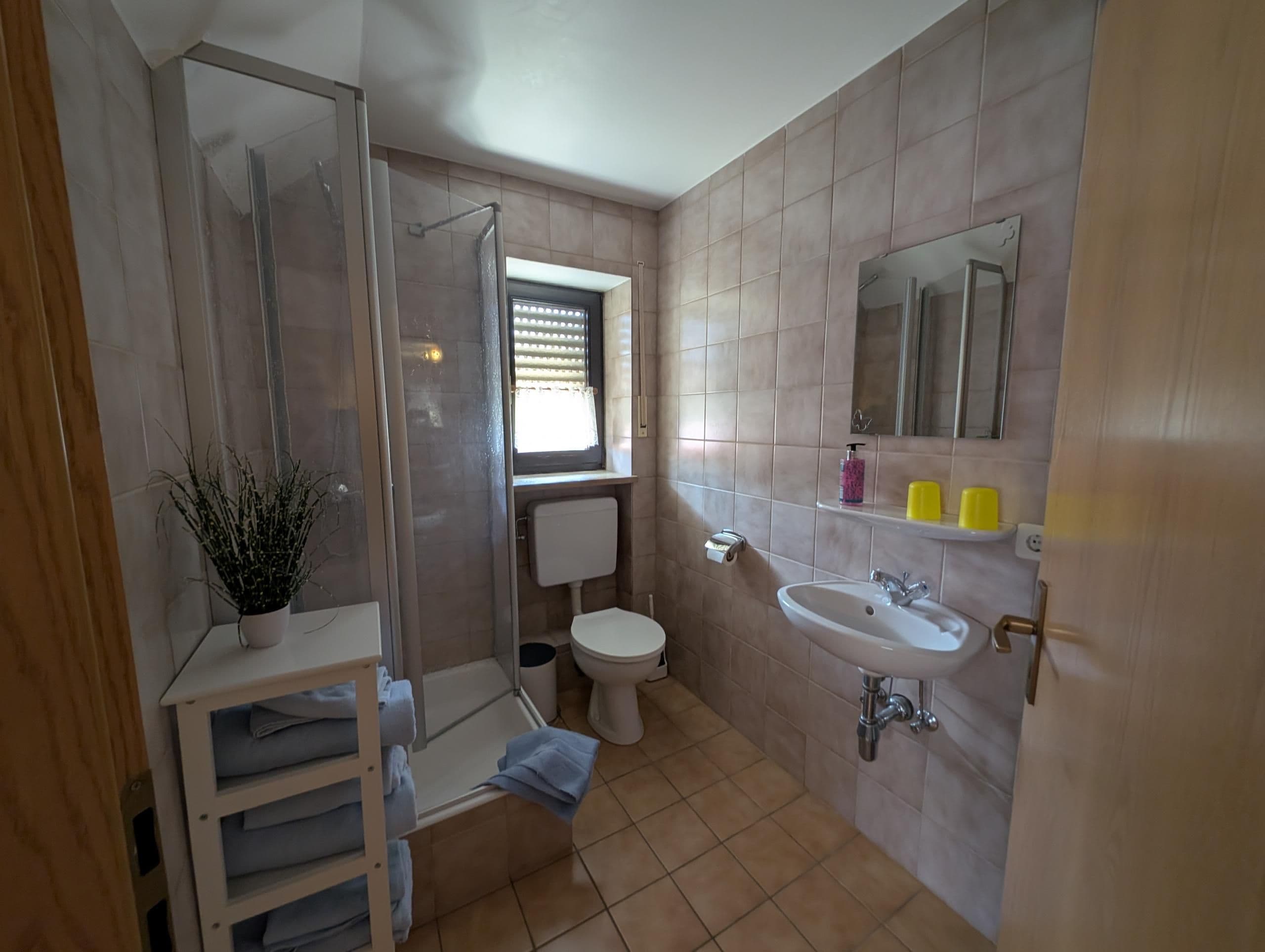Un baño con ducha, inodoro, lavamanos y una ventana.