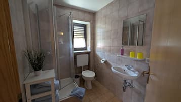 Un baño con ducha, inodoro, lavamanos y una ventana.