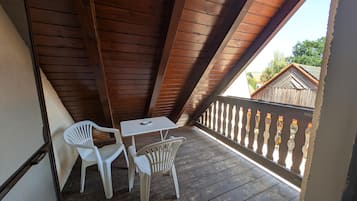 Un balcón de madera con una mesa y dos sillas, con vistas a una zona residencial.