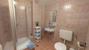 A bathroom with a shower, toilet, sink, and a mirror.