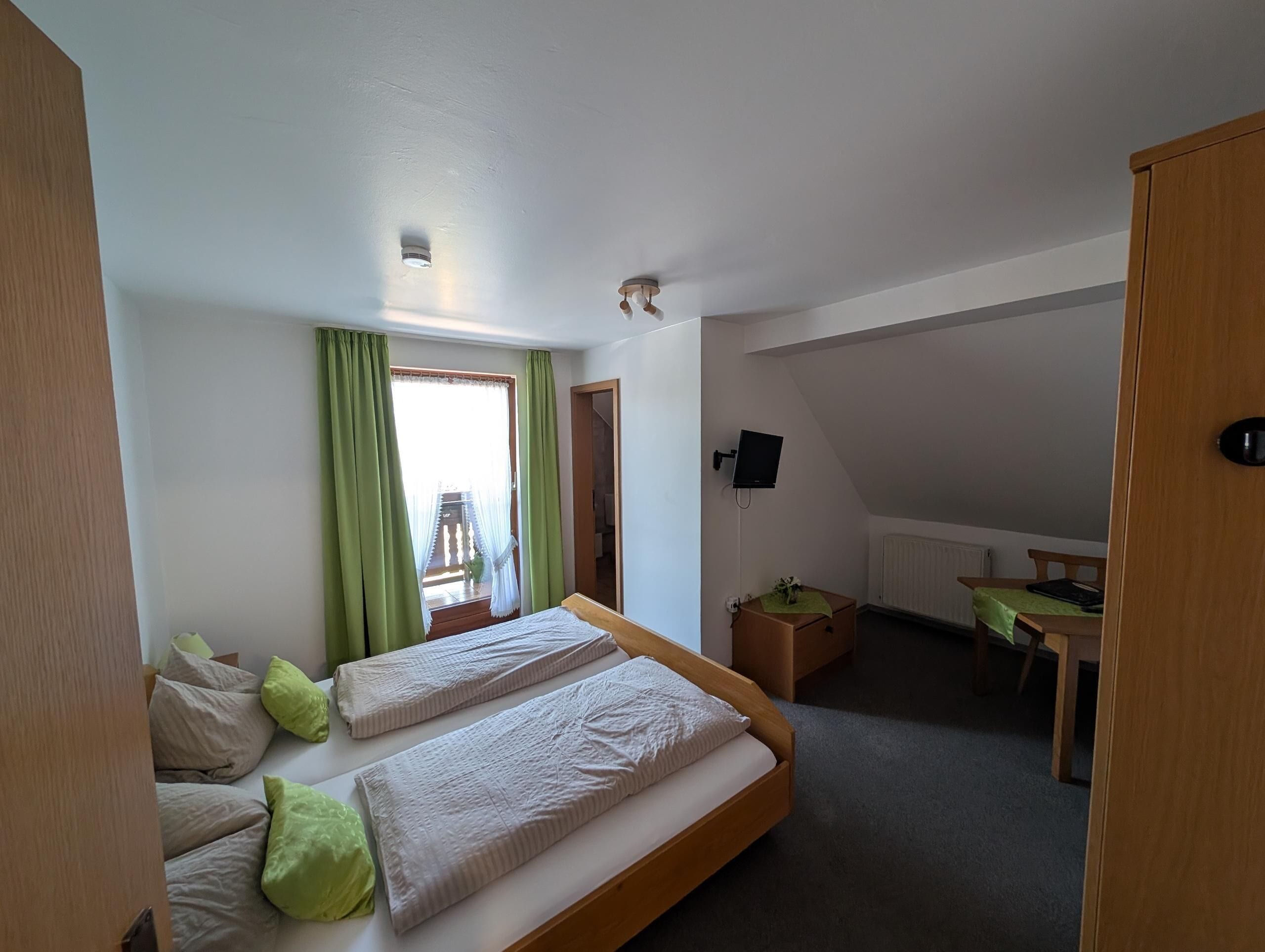 A room with a bed, a desk, a chair, and a television.