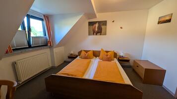 Une chambre à coucher avec un grand lit, un radiateur, une fenêtre avec des rideaux et un luminaire au plafond.