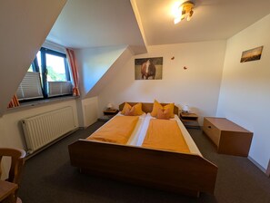A bedroom with a large bed, a radiator, a window with curtains, and a ceiling light fixture. - Landgasthof Pension zum Ross (Berg bei Neumarkt in der Oberpfalz)