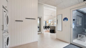 Um interior moderno com área de lavanderia, sala de jantar e vista através de uma porta de vidro.
