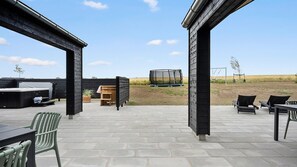 Eine Außenpatio mit Whirlpool, Sitzgruppe und Trampolin.