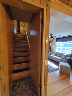 A wooden staircase leading to a room with a sofa and a patterned rug.