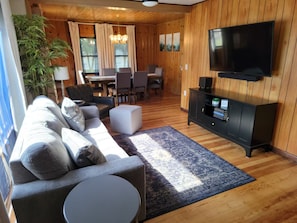 A modern living room with a sofa, ottoman, and a flat-screen TV mounted on the wall.