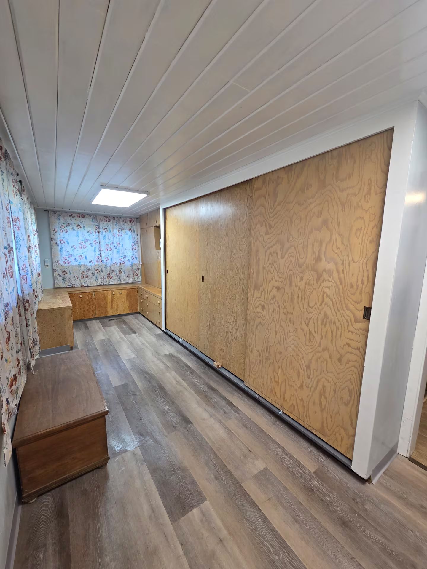 A room with a wooden floor, a bench, and a large sliding door.
