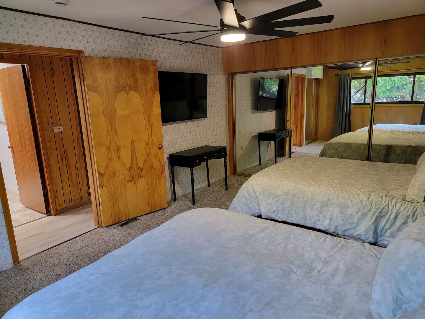 Une chambre avec deux lits, une télévision, une armoire en bois et un miroir.
