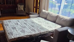 A room with a large bed, a sofa, a small table, and a bookshelf. - Carlton Cottage (Burney)