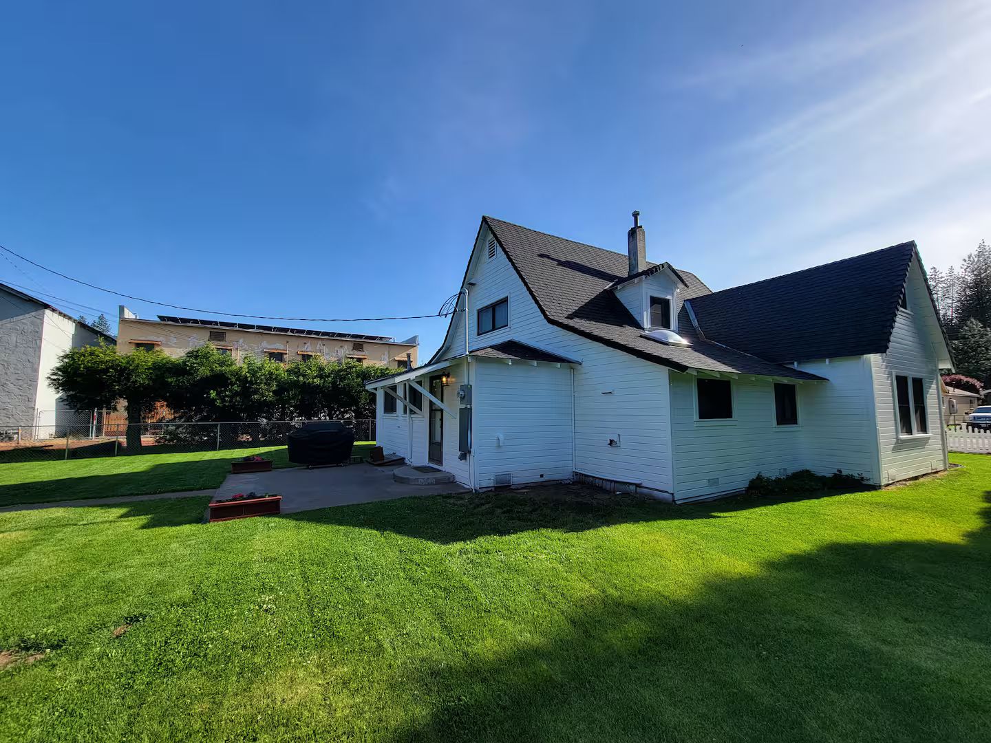 A single-story house with a sloped roof, a visible chimney, and a well-maintained lawn.