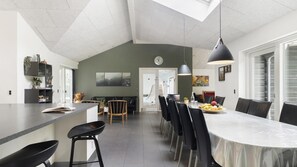 A modern kitchen with a central island, dining area with chairs and a table, and a large window. - VillaVilla 985 - Øster Hurup, Østjylland (Hadsund)