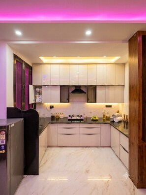 A modern kitchen with white cabinets, a black refrigerator, and a marble floor. - 2BHK Flat | Near Jaipur Airport | Rooftop Flights View (Jaipur)