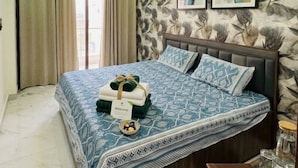 Quarto com cama, cortinas, ventoinha no teto e obras de arte nas paredes.