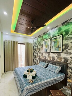 A bedroom with a bed, curtains, a ceiling fan, and wall art. - 2BHK Flat | Near Jaipur Airport | Rooftop Flights View (Jaipur)