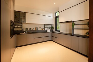 A modern kitchen with built-in appliances, a window, and a view of greenery outside. - Sea Cloud Residence (Tambon Wichit)