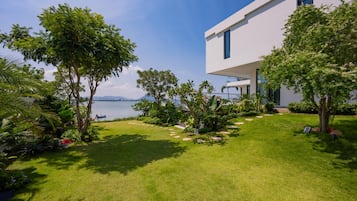 Uma casa moderna com gramado bem cuidado e vista para a água.