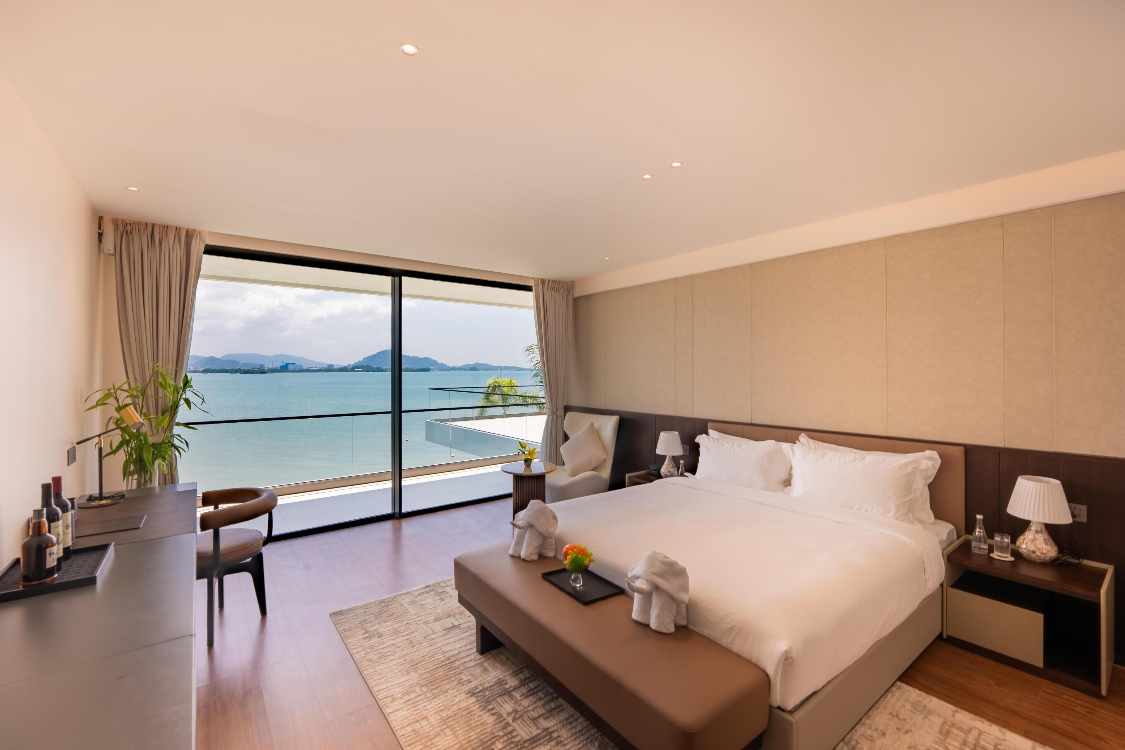 Quarto de hotel moderno com uma cama grande, uma escrivaninha e vista para o mar.