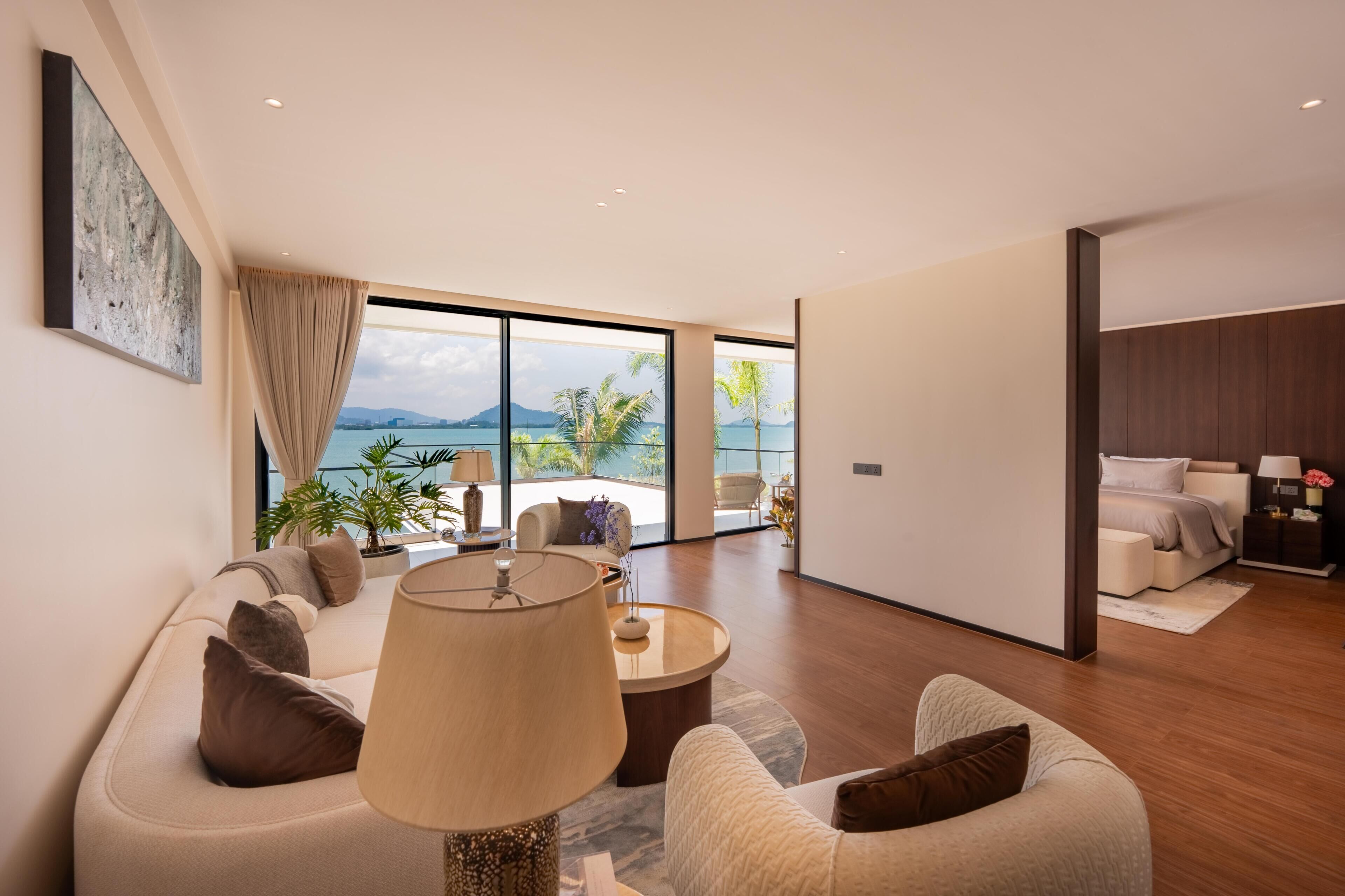 Un salon moderne doté d’une grande fenêtre, d’un ensemble de canapés, d’une table basse et offrant une vue sur la mer.